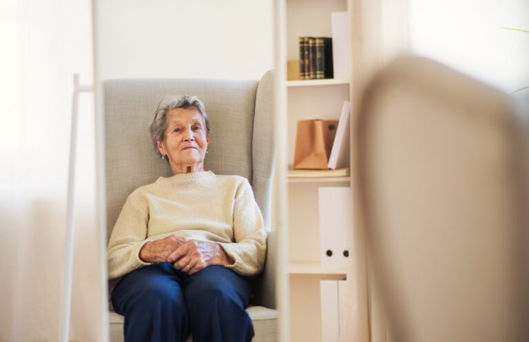 A portrait of a senior woman sitting at home, looking at camera. Copy space